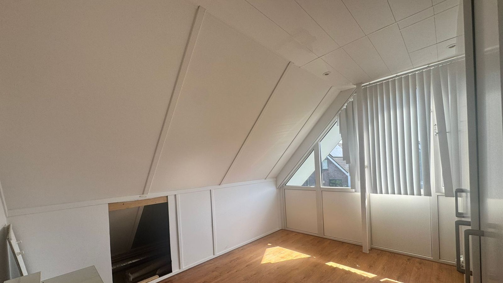 De zolderkamer vóór de verbouwing: wit beschot, knieschotten met luiken en één dakkapel met lamellen