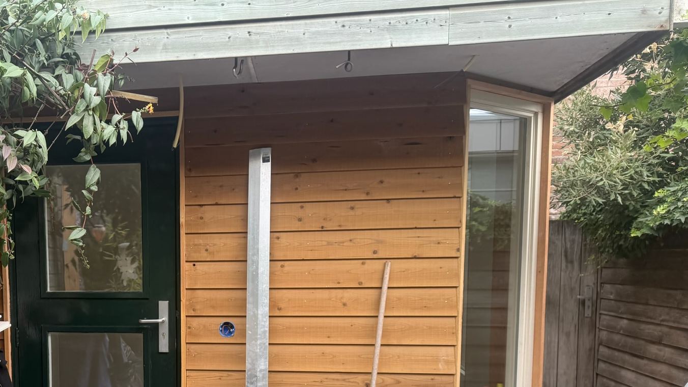 Uitbouw met houten gevelbekleding, hoekraam en een eigen buitendeur, vlak voor de oplevering