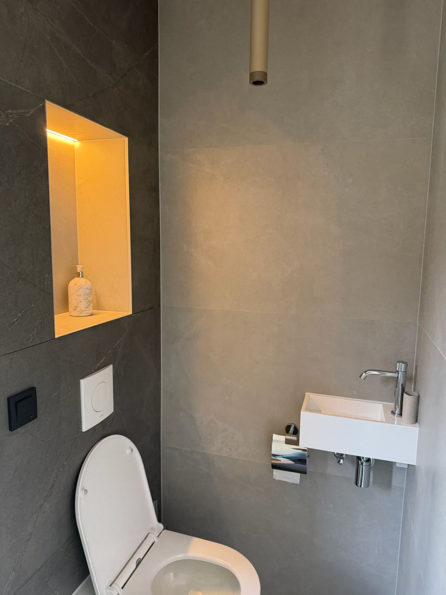 Apart toilet met zwevend closet, wandfonteintje en een verlichte nis