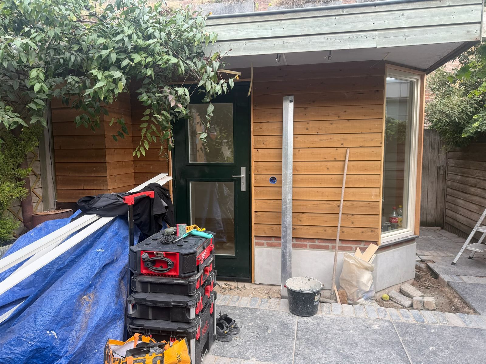 Uitbouw met plat dak, op de grond en tegen de achtergevel van de bestaande woning